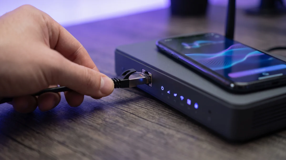Netwerkkabel wordt in een router gestoken, met een telefoon ernaast